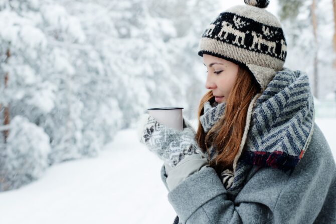 冬の屋外でコーヒーを飲む女性