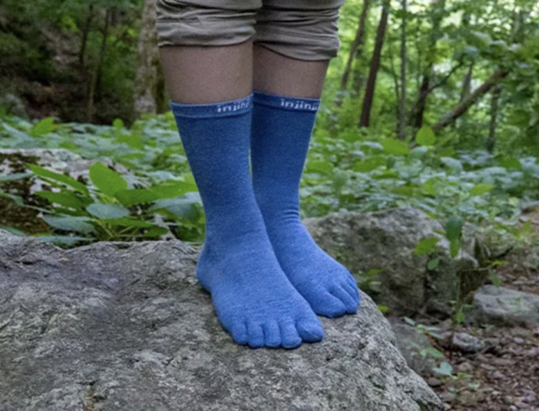 青い５本指の靴下を履き岩の上に立っている男性