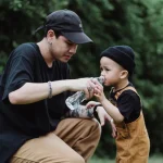 アウトドアでお父さんが子供にペットボトルのお水を飲ませているところ