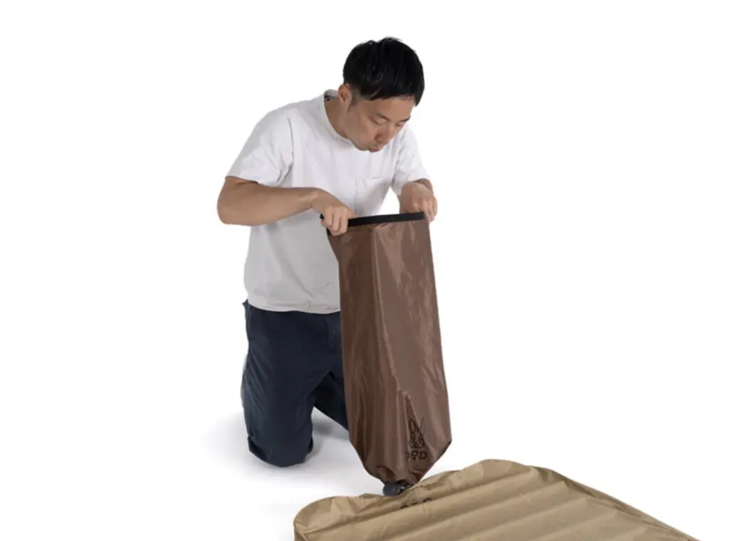 ソトネノキワミエアー収納袋の中をのぞ置く男性