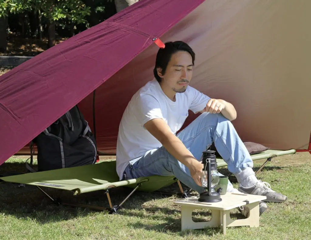 タープの下のローコットに座る男性